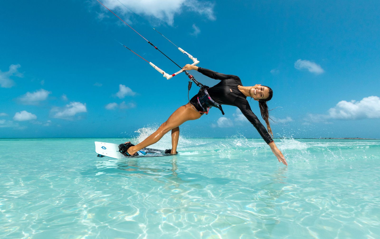 Duotone kitesurfer riding waves in turquoise water